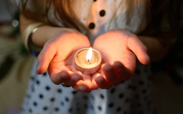 Bir kızın avuç içi yanan mum