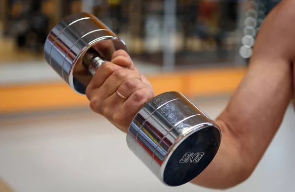 Kaslı bir kolu bir dumbbell tutar. Spor salonu. Bir spor salonu için donatım.