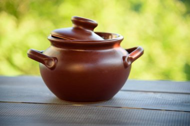 Gri bir ahşap masa üzerinde toprak kap. Lezzetli ve sağlıklı yemek yapma kavramı.