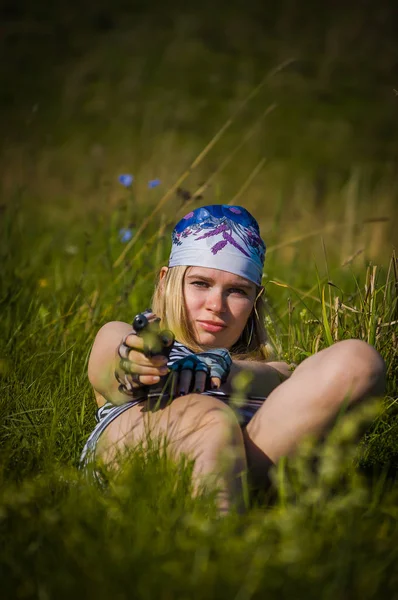 Young girl with a gun in green grass outdoors