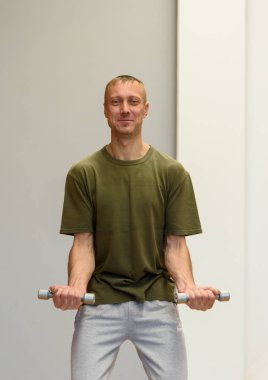 Spor giyim kendine güvenen genç yakışıklı adam, spor salonunda dumbbells ile egzersizleri. Kategori spor