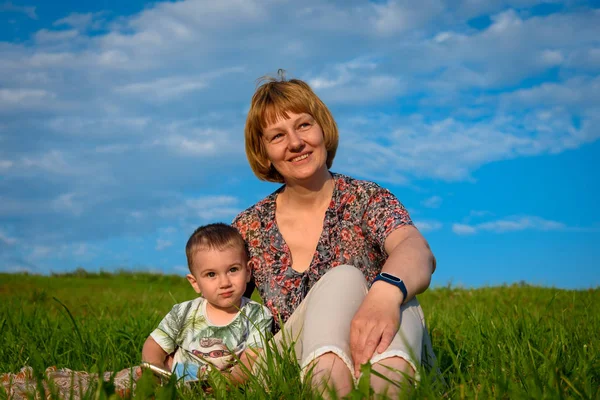 Küçük bir çocuk ile kadın bir çayırda oturup mesafe bakmak