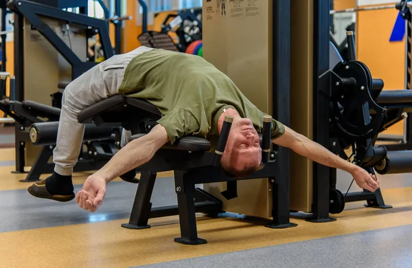 Tired man in the gym behind a fitness station.