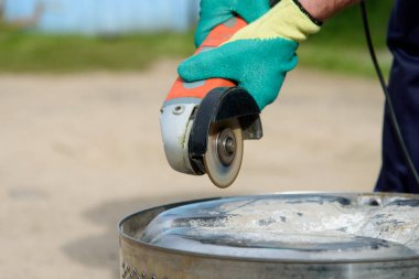 İşçi, metali açı öğütücüyle kesiyor.