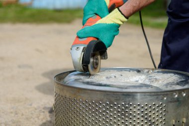 İşçi, metali açı öğütücüyle kesiyor.