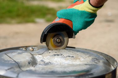 İşçi, metali açı öğütücüyle kesiyor.