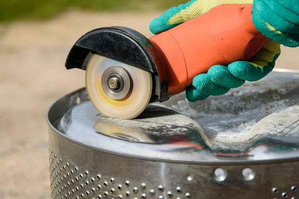 İşçi, metali açı öğütücüyle kesiyor.