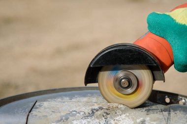 İşçi, metali açı öğütücüyle kesiyor.