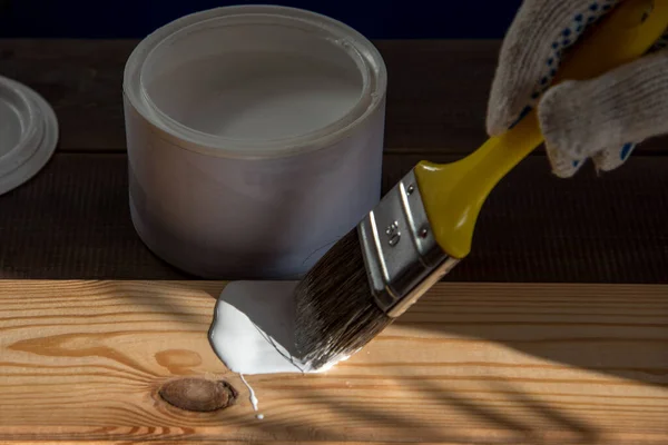 Beyaz boya ve boya fırçası. Örtülü ahşap tahta