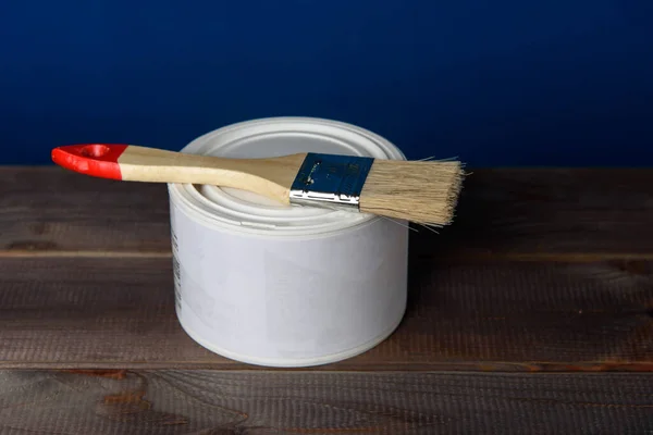 Bir kutu beyaz boya ve ahşap bir masada boya fırçası..