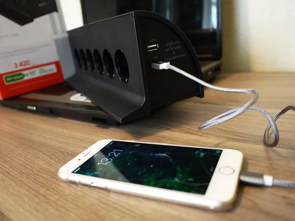 The smartphone is charging, is connected to the outlet and gaining the capacity of the battery , details and close-up