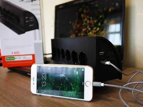 The smartphone is charging, is connected to the outlet and gaining the capacity of the battery , details and close-up