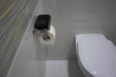 Toilet paper holder (with shelf for smartphone) in toilet, interior details and close-up clipart