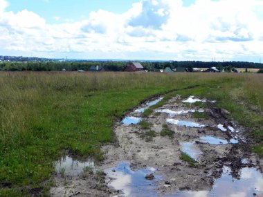Köydeki köy yolu. Şehir dışında su birikintileri ve kötü pokrytiem ile yol. Ayrıntılar ve yakın çekim.