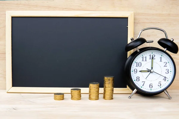 Money coins bar alarm clock and chalkboard on wood table represents a plan for saving money Time management For investment for the future. - Savings money concept.