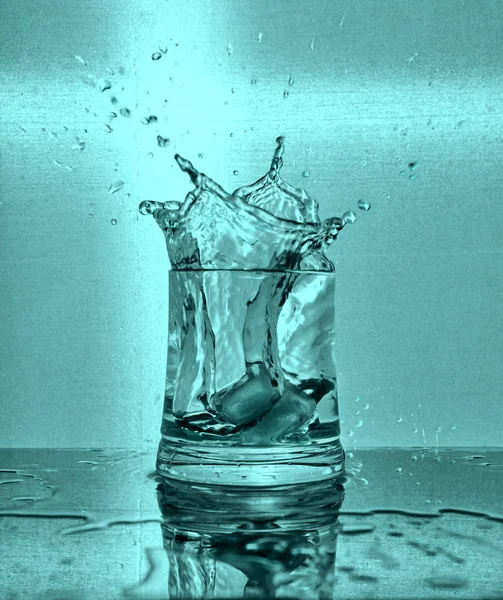 Isbitar Stänk Glas Vatten Blå Bakgrund — Stockfoto