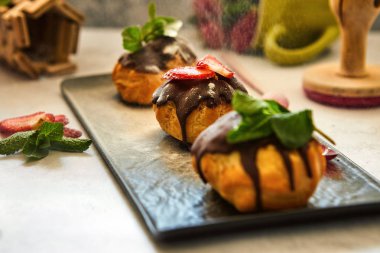 Siyah bir tabak üzerinde eritilmiş çikolata ile profiterol pasta yığını