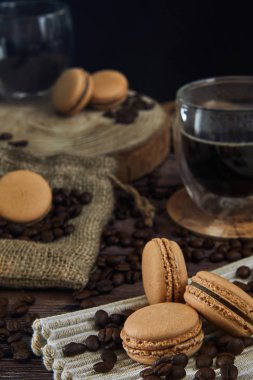 Eski ahşap mutfak masasında kahve bardağı, fasulye ve macaroons. Yan görünüm.