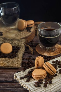 Eski ahşap mutfak masasında kahve bardağı, fasulye ve macaroons. Yan görünüm.