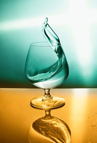 Turkiz オレンジの背景に波のある水のグラス 水と飛沫のシンボルデザインのガラス 概念設計 — ストック写真