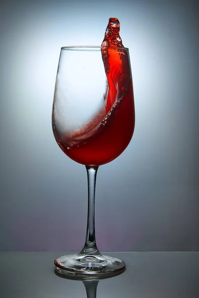 青の背景に波と赤ワインのガラス ワイングラスとスプラッシュシンボルデザイン — ストック写真
