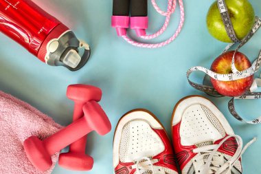 ruits, halter, su şişesi, halat, spor ayakkabı ve metre mavi bir arka plan üzerinde.