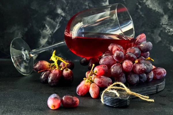 Verre de vin avec raisins sur un support en bois noir — Photo