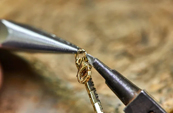 ewelry production. The process of connecting a golden lock with a bracelet with the help of two jewelry pliers