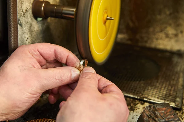 Jewelry production. Jeweler polishes a gold ring on a sander