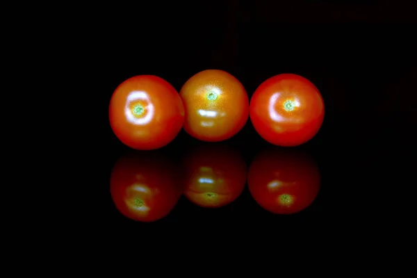 Bando brilhante e suculento de tomates cereja vermelhos isolados no preto — Fotografia de Stock