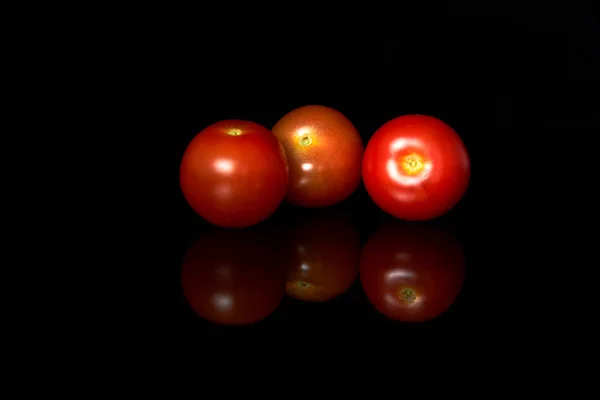 Błyszczący i soczysty bukiet czerwonych pomidorów Cherry wyizolowanych na czarnym — Zdjęcie stockowe