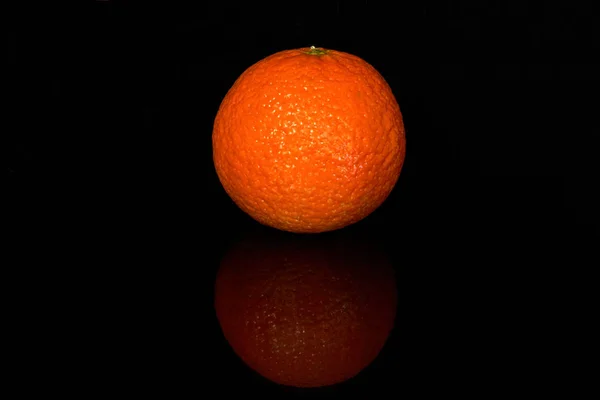 Fresh juicy tangerine with reflection on black — Stock Photo, Image