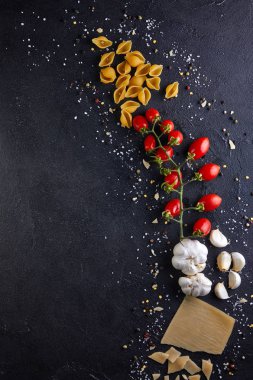 Siyah arka planda makarna pişirmek için malzemeler.