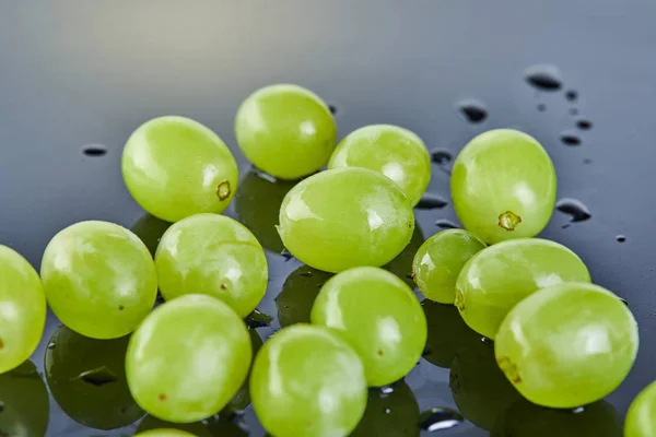 Raisins verts frais avec des gouttes d'eau sur fond gris — Photo