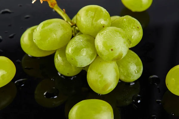 Raisins verts frais avec des gouttes d'eau sur un fond sombre — Photo