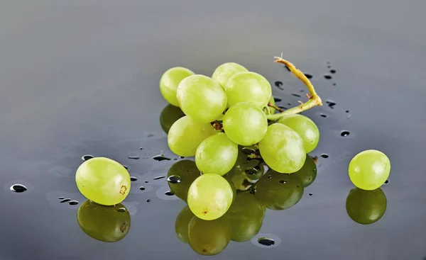 Raisins verts frais avec des gouttes d'eau sur fond gris — Photo
