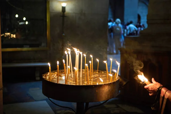 Många kyrkljus brinner i mörkret. Ljus i den heliga Sepulchers kyrka i Jerusalem. — Stockfoto
