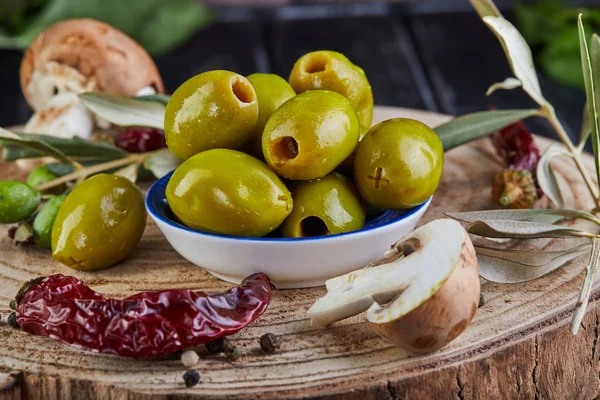 Yeşil taze zeytin, kırmızı biber ve taze mantar ile natürmort zeytin ağacı yaprakları koyu ahşap yakın