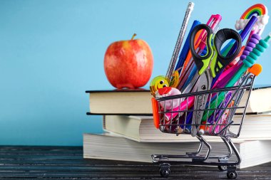 Kitap yığını ve kopya alanı ile bir elma ile mavi bir arka plan üzerinde okul kaynağı ile Alışveriş sepeti Banner. Okula geri dön