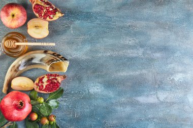 Rosh hashanah - Yahudi Yeni Yıl tatili konsepti. Geleneksel semboller: Bal kavanozu ve narlı taze elmalar ve mavi arka planda shofar boynuzu. Metin için alanı kopyala.