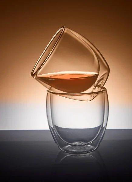 Dos vasos para café o té, uno encima del otro con té en el vaso superior con reflejo — Foto de Stock
