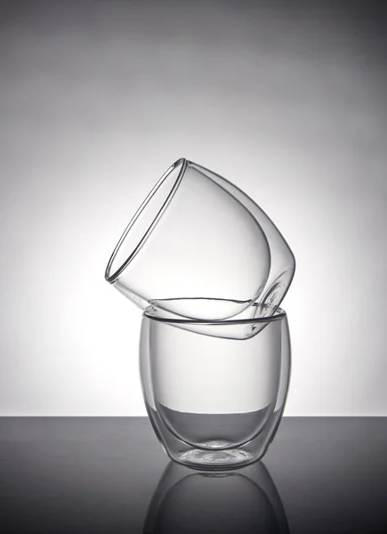 Dos vasos para café o té, uno encima del otro sobre un fondo gris con reflejo — Foto de Stock