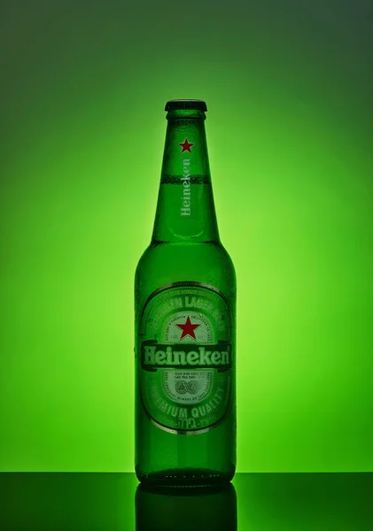 Láhev piva Heiniken na zeleném pozadí s podsvětlenou a reflexní. — Stock fotografie
