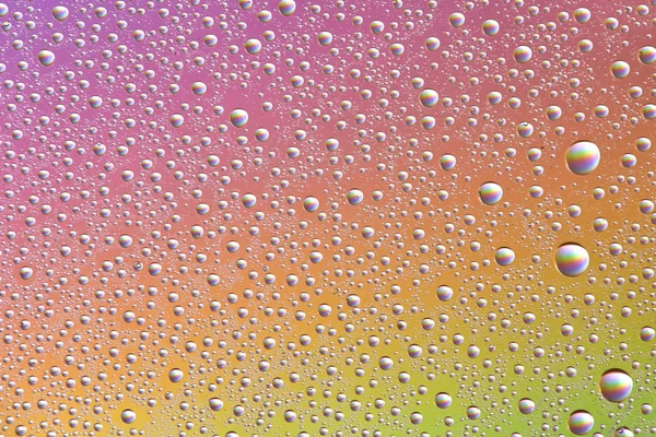 Gotas en vidrio de diferentes tamaños y colores sobre un fondo de color, textura — Foto de Stock