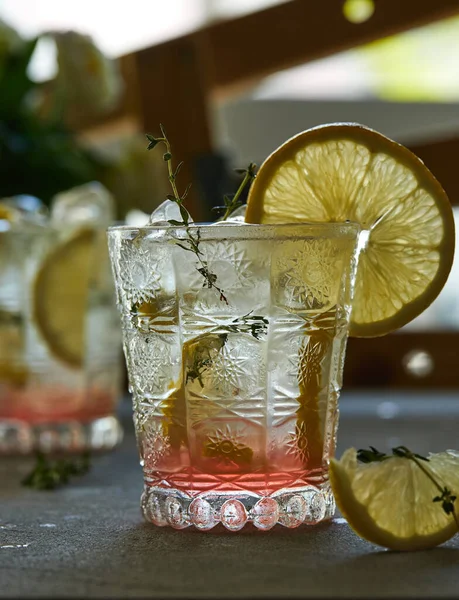 Boisson fraîche au citron et thym dans un verre sur fond gris — Photo