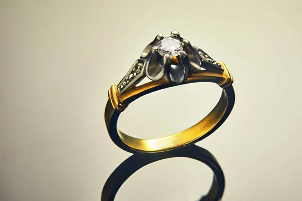Guld ring i vitt och gult guld med diamanter på en bakgrund med en lutning och reflektion. Produktion av smycken — Stockfoto