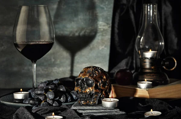 Skull, candles, wine, grapes, old lamp on a dark background. Halloween concept
