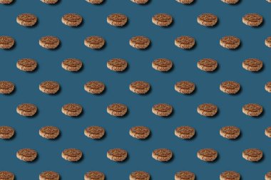 İyi kızartılmış hamburger pirzolası, mavi arka planda baharat desenli..