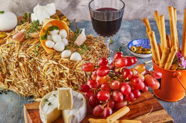 Bebek mozzarella, peynir ve sarımsaklı ve üzümlü Fresca mozzarella ve mavi arka planda ahşap bir stantta bir bardak şarap. İtalyan lezzetleri..