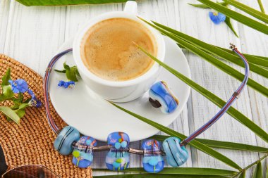 Mücevherlerle yaz konsepti. Kahve, palmiye yapraklı şapka ve beyaz ahşap arka planda boğucu takılı bir yüzük..